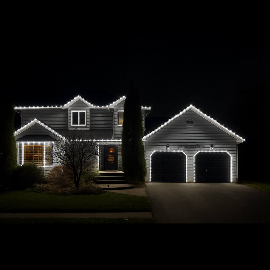 Cool white C9 Christmas lights highlighting peaks, garage arches and window trim on a two-storey home in Clarington